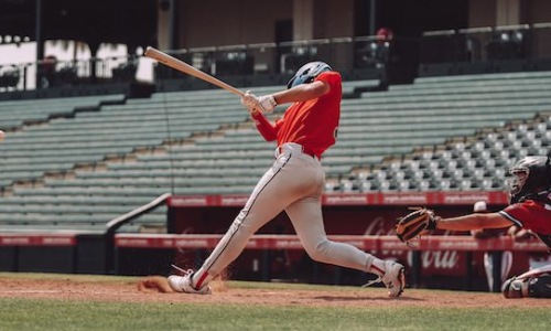 Baseball player swinging bat in empty stadium